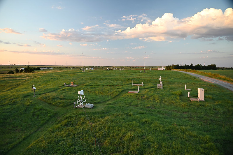 An ARM instrument cluster collects data at the Southern Great Plains Central Facility as wind turbines operate in the distance.