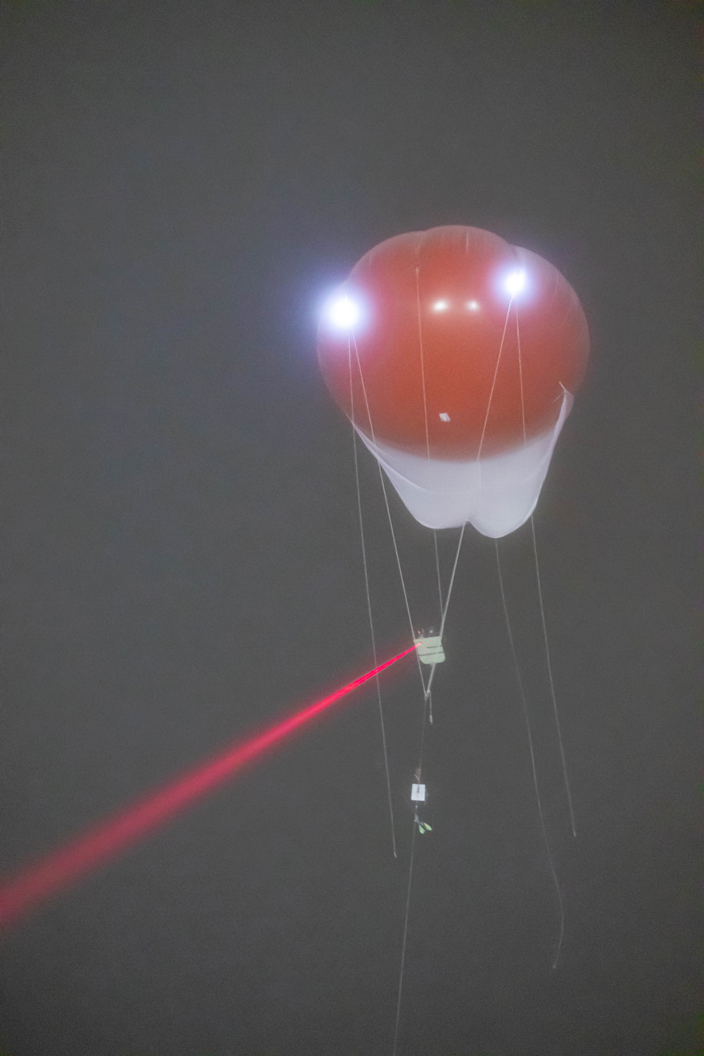 Tethered balloon system flies at Oliktok Point, Alaska, in ice fog with red laser shining from instrument platform
