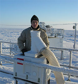 A researcher checks the GVR antennae on a cold, crisp day at the ARM site in Barrow, Alaska. The radiometer is inside the insulated box beneath the antenna; the data is collected and displayed on the computer inside the instrument shelter.