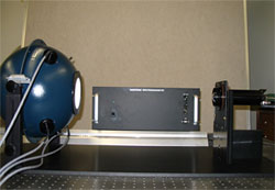 An integrating sphere (left) is used to calibrate the optic element (right). The spectrometer itself is in the middle of the photo.