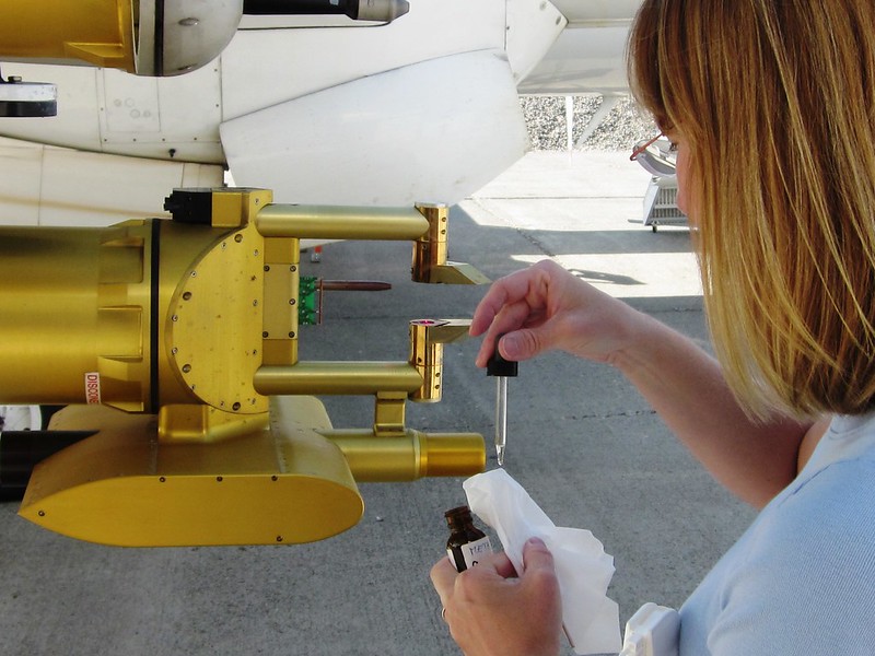 Using a dropper, Jennifer Comstock applies liquid to a cloth to clean a research aircraft probe.