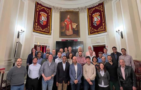 A group photo underneath historic images and paintings in the main hall of the Cardenal Lorenzana Palace