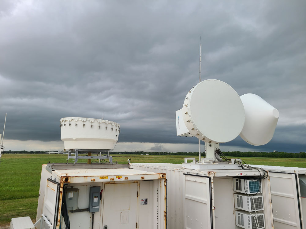 ARM radars are in the foreground as convection builds nearby, darkening the sky.