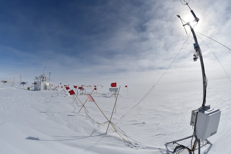 Instruments set up across the West Antarctic Ice Sheet with sun breaking through the clouds overhead