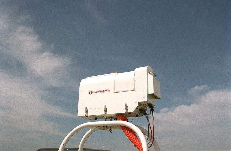 Clouds float behind a microwave radiometer.