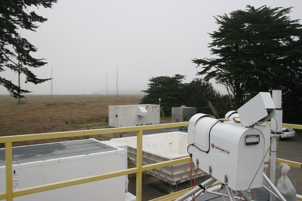 A microwave radiometer sits on the roof of a mobile facility container on a cloudy day.
