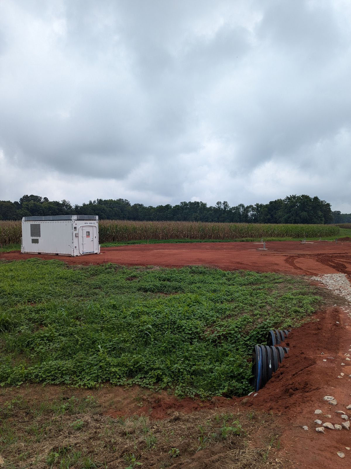 Clouds block the sun at the Bankhead National Forest supplemental site near Courtland, Alabama. A single ARM container sits between crops and a culvert.