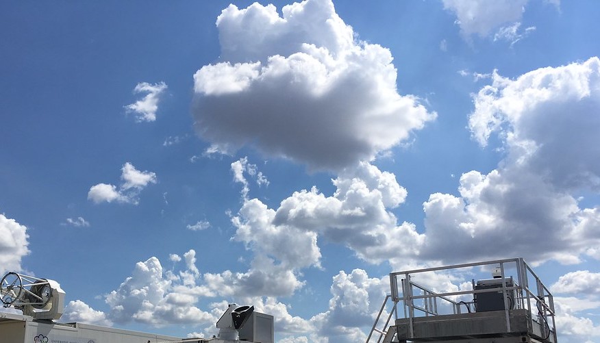 Clouds float above lidars on a sunny day at the Southern Great Plains atmospheric observatory.