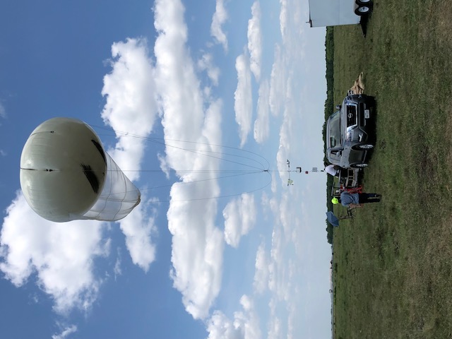A white tethered balloon stretches into the sky on a rain-free day in Guy, Texas.