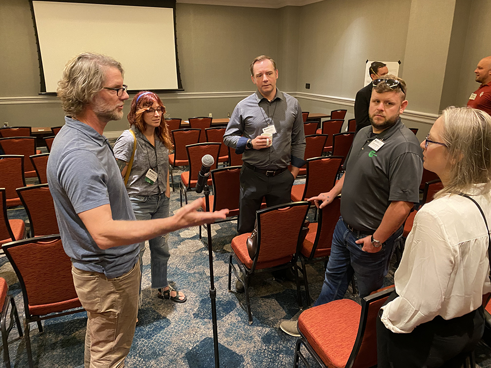 Matt Shupe gestures while talking to a group of fellow high-latitude working group participants standing around him.