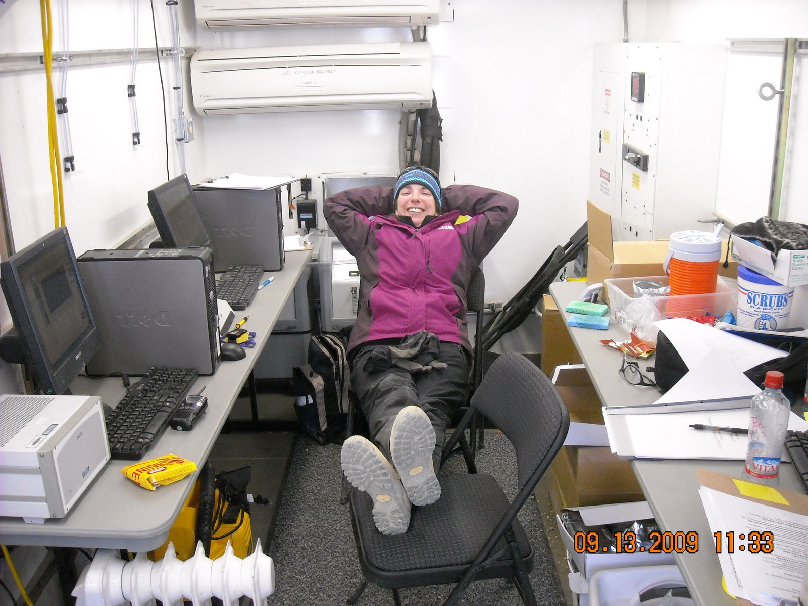Jen Delamere kicks back in a chair with her hands behind her head.