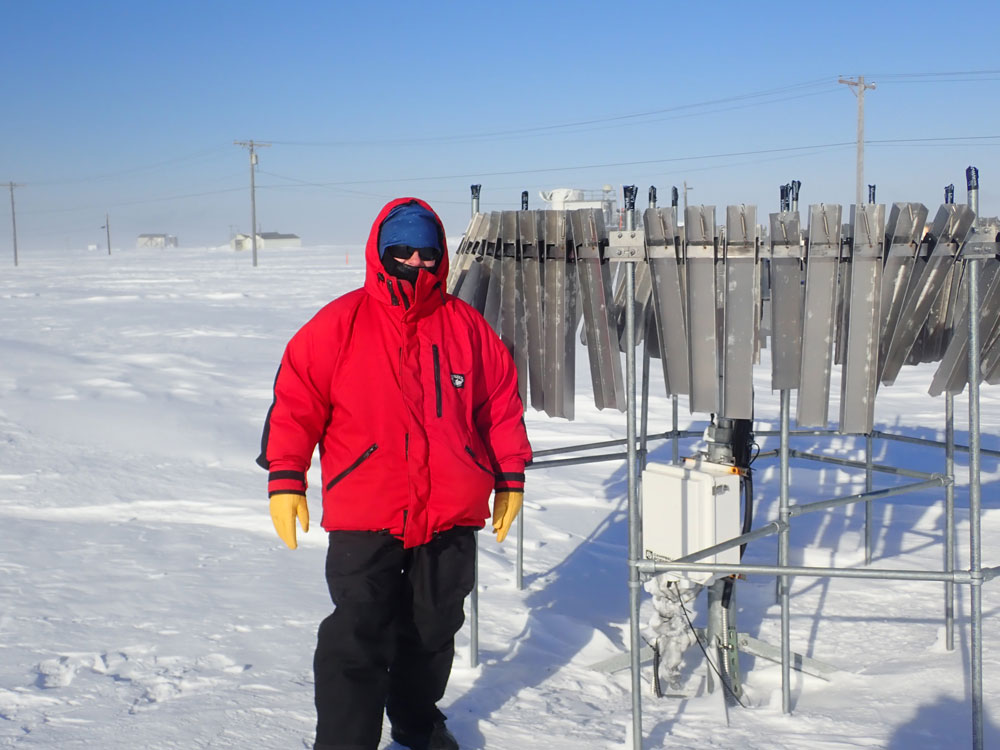 Jen Delamere stands out in the cold wearing a big red parka, gold gloves, and black snow pants.