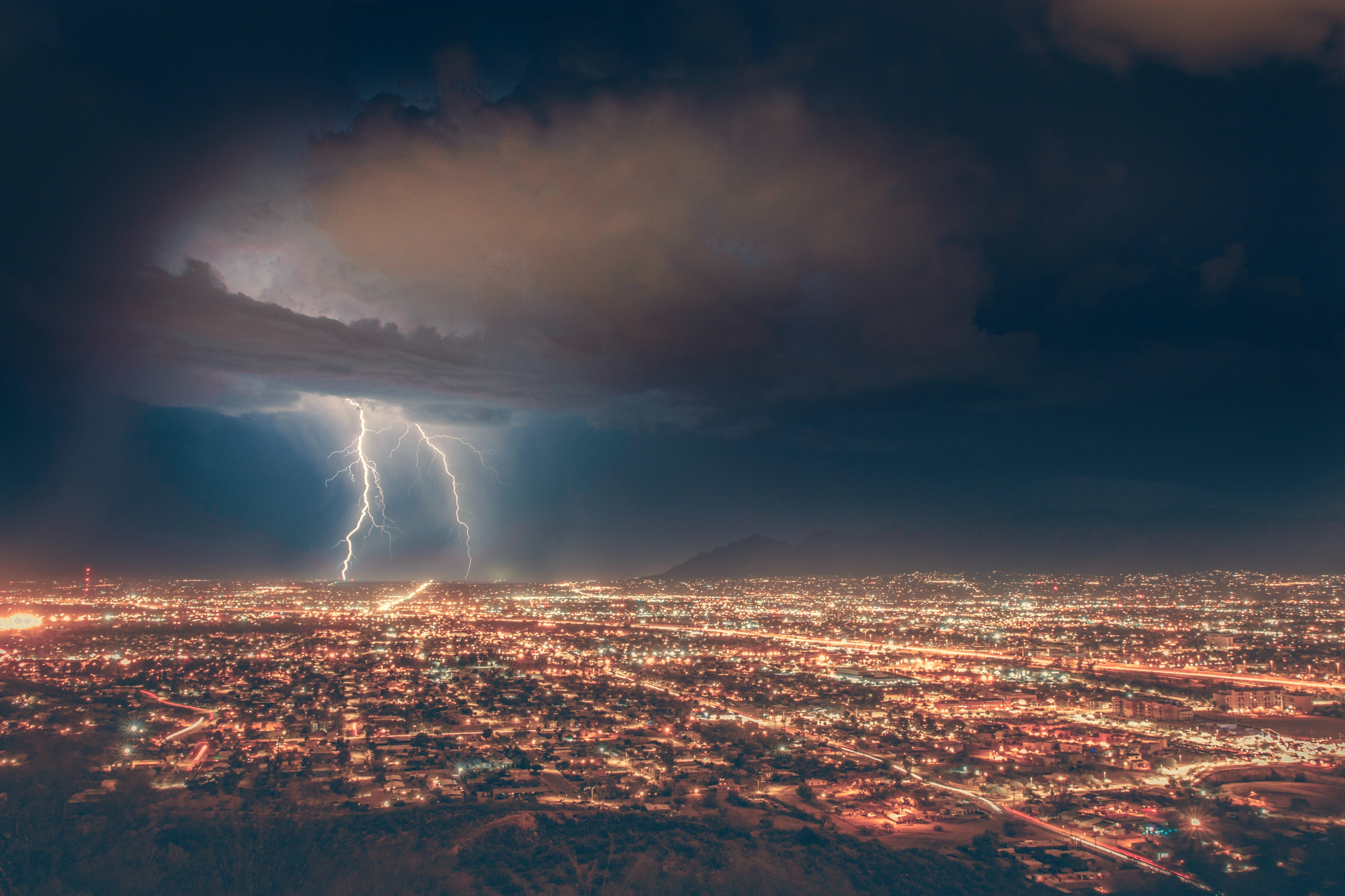 Two large lightning bolts crackle over a city.