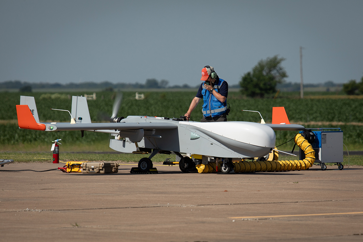 A person stands on the tarmac while preparing the ArcticShark uncrewed aerial system for a flight.