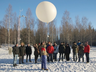 A group gathers in a forest to watch a man launch a weather balloon during the BAECC campaign in Finland.