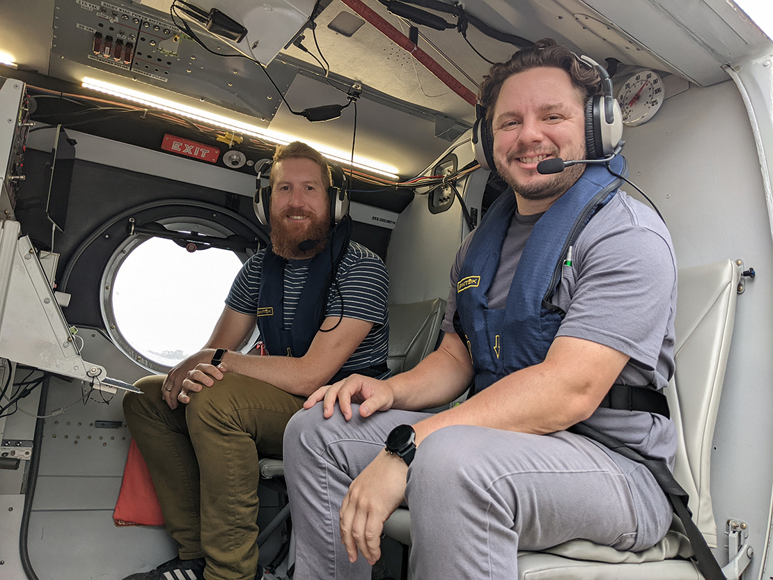 Mikael Witte and Mason Leandro sit next to each other in the Twin Otter wearing their headsets.