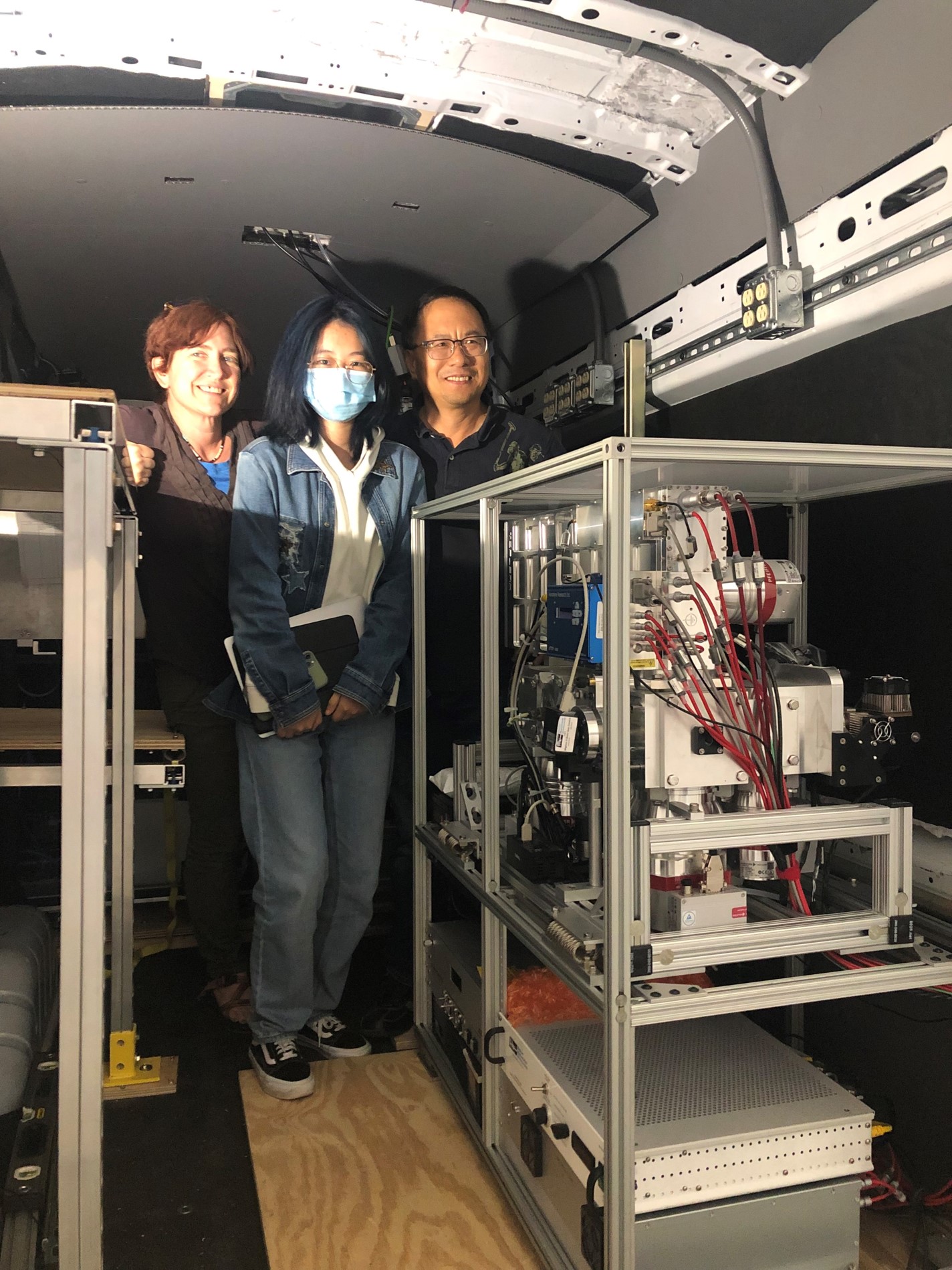 Sarah Brooks poses with two of her students in a van with instrumentation on carts.