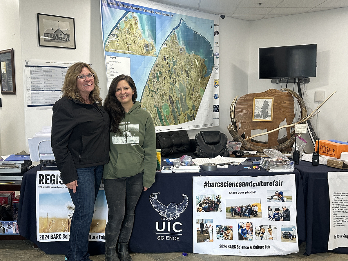 Valerie Sparks (left) poses with Telayna Wong, a UIC Science project manager, in front of a table at the Barrow Arctic Research Center (BARC) Science and Culture Fair in August 2024. Photo is courtesy of Valerie Sparks, Sandia National Laboratories.