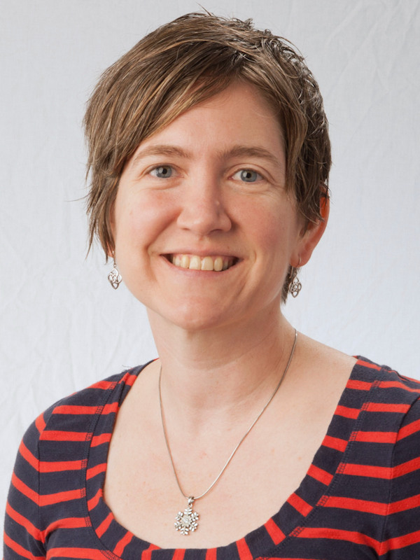 Sarah Brooks smiles for the camera while wearing a striped shirt and a necklace with a snowflake pendant.