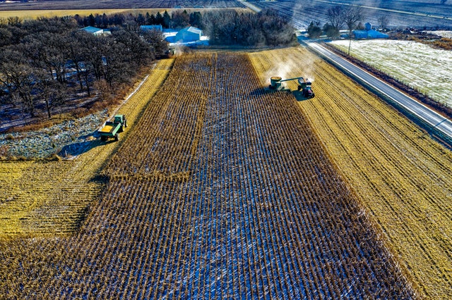 A tractor kicks up dust while motoring across farmland.