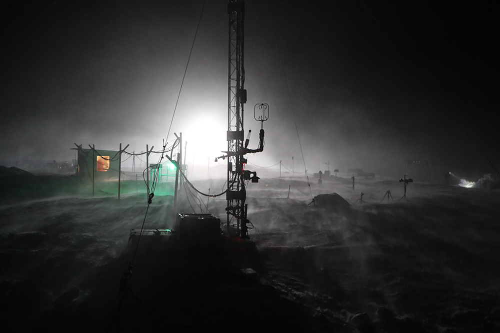 Light illuminates snow blowing around a tower installed during the MOSAiC expedition. 
