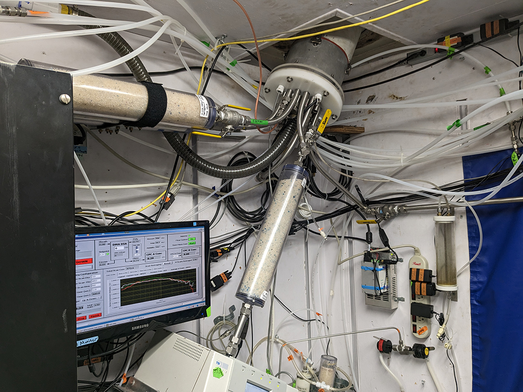 A computer screen and various intakes, filters, and tubing are connected within an instrument container.