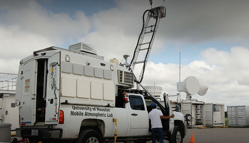 A person holds open the front passenger door while looking inside the University of Houston Mobile Atmospheric Lab.